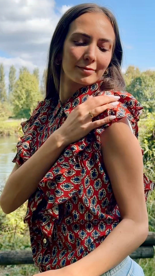 Donna indossa camicia estiva ecosostenibile in cotone indiano con stampa geometrica rossa, outfit estivo raffinato.