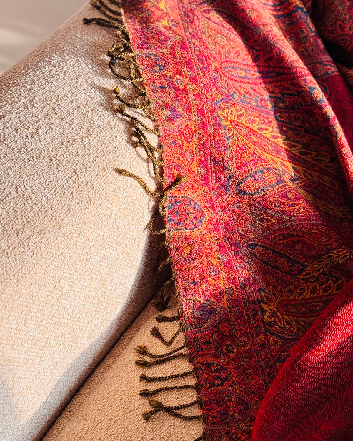 Coperta in lana jacquard rossa che scende dal bracciolo del divano, con frange