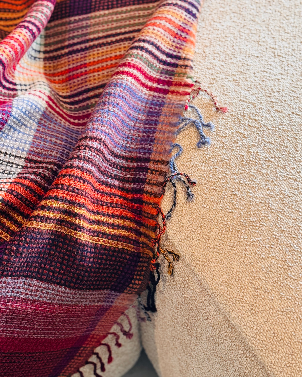 Plaid in lana merino a quadri che scende dal divano, con frange