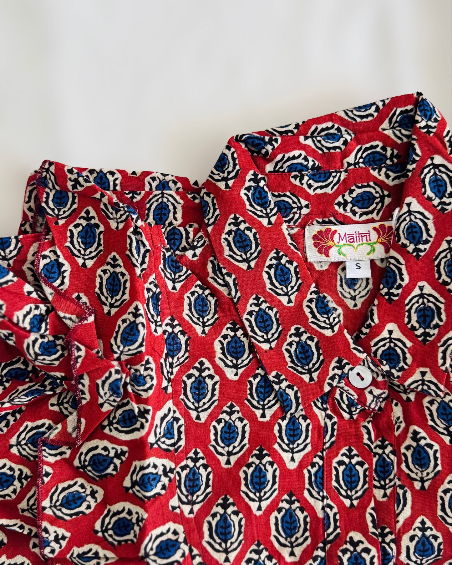 Primo piano della trama del cotone e della stampa artigianale a blocchi rossa su tessuto naturale.