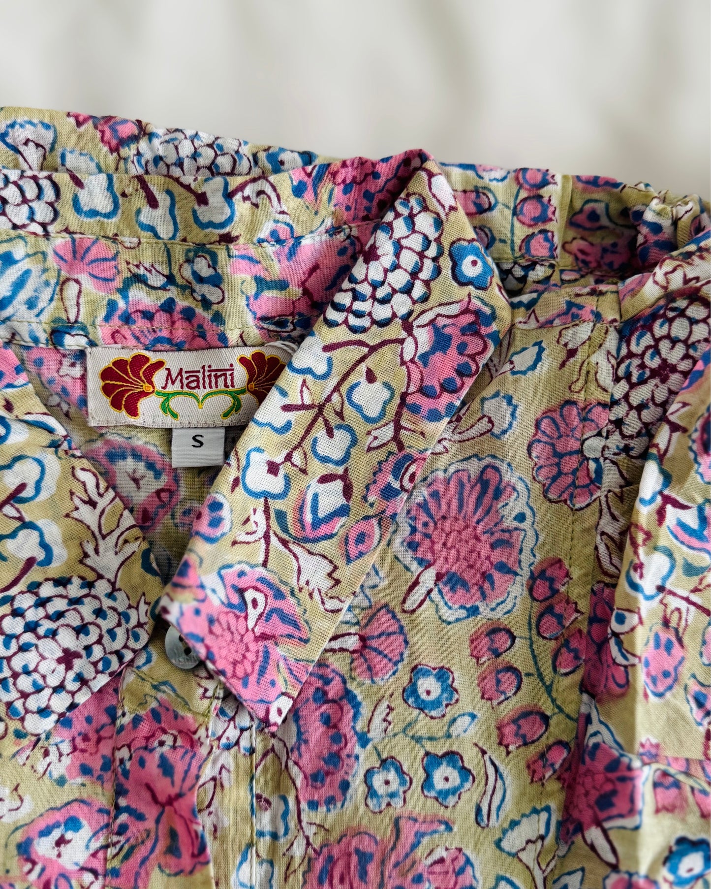 Camicia smanicata da donna in cotone beige con volant, stampa floreale block print rosa e laccetto regolabile in vita.