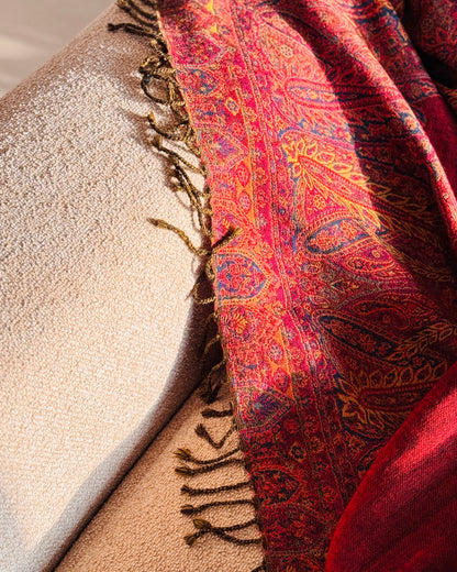 Coperta in lana jacquard rossa che scende dal bracciolo del divano, con frange