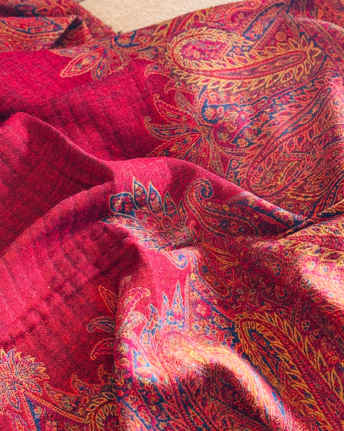 Dettaglio del paisley oro e blu su fondo rosso