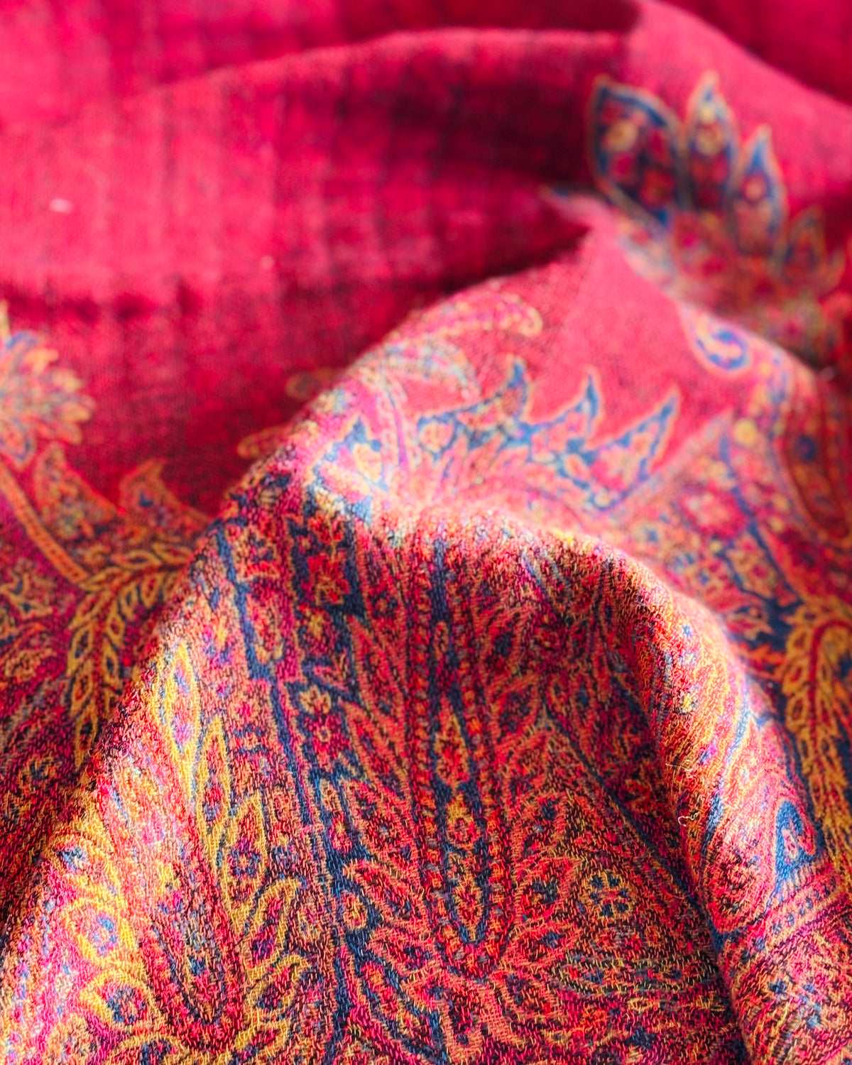 Pieghe della coperta rossa, bordo paisley e fondo rosso pieno