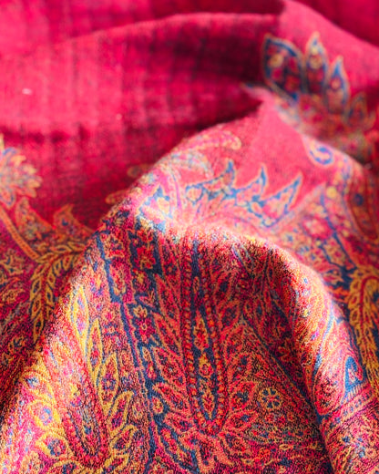 Pieghe della coperta rossa, bordo paisley e fondo rosso pieno