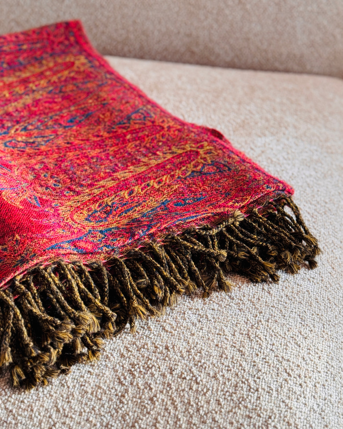 Coperta paisley rossa piegata, dettaglio delle frange marrone e oro