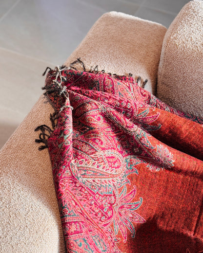 Coperta paisley arancio rame appoggiata sul bracciolo del divano