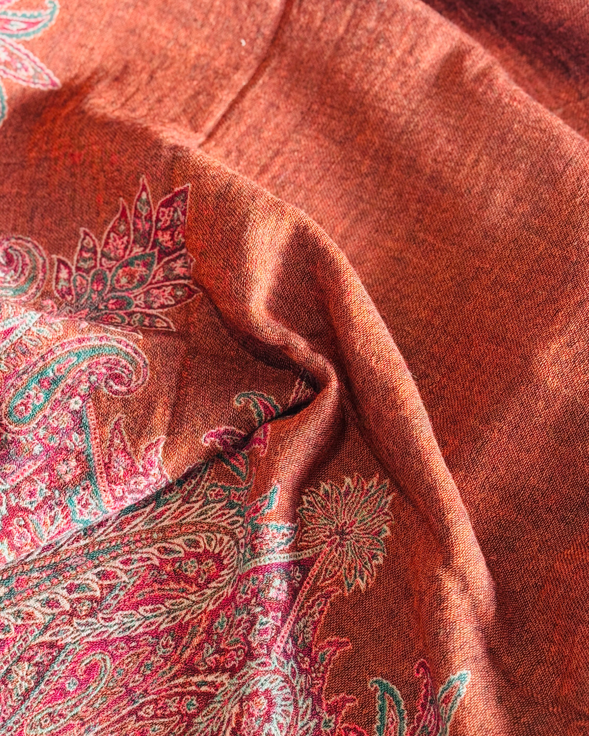 Dettaglio del fondo arancio rame e dei motivi paisley fucsia e verdi