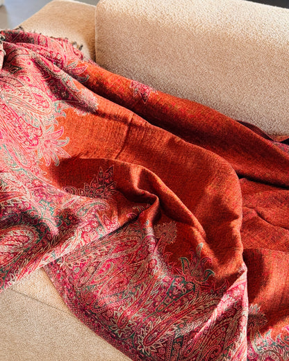 Coperta in lana arancio rame e fucsia aperta sul divano