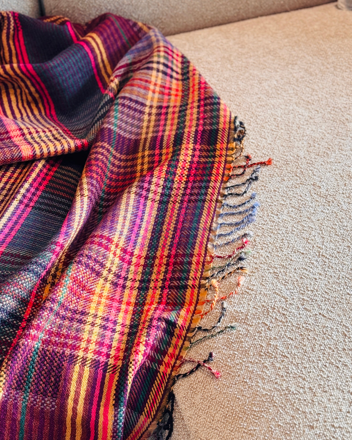 Plaid in lana merino tartan appoggiato sul bracciolo del divano