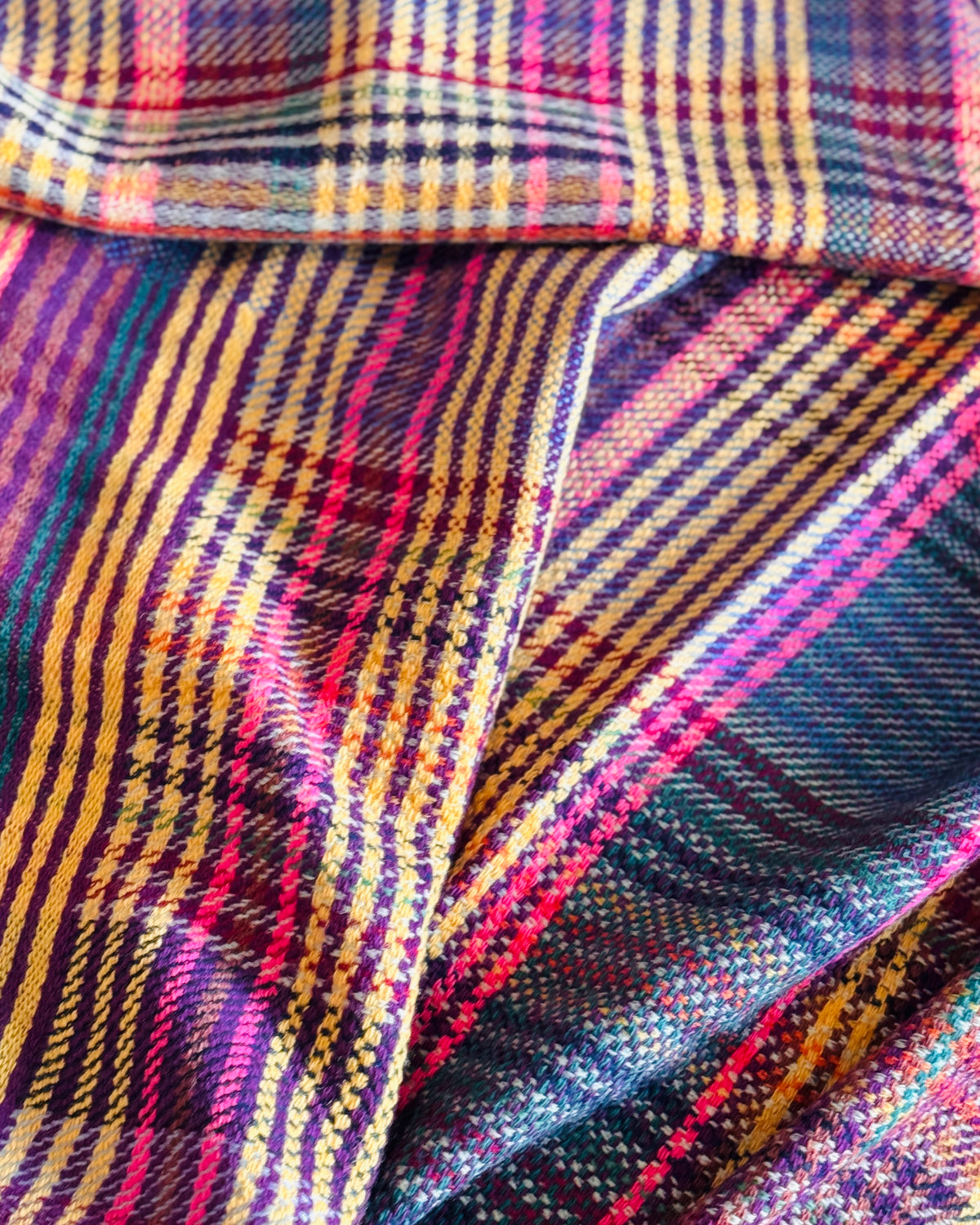 Dettaglio della trama tartan in lana merino: viola, senape, magenta e blu notte