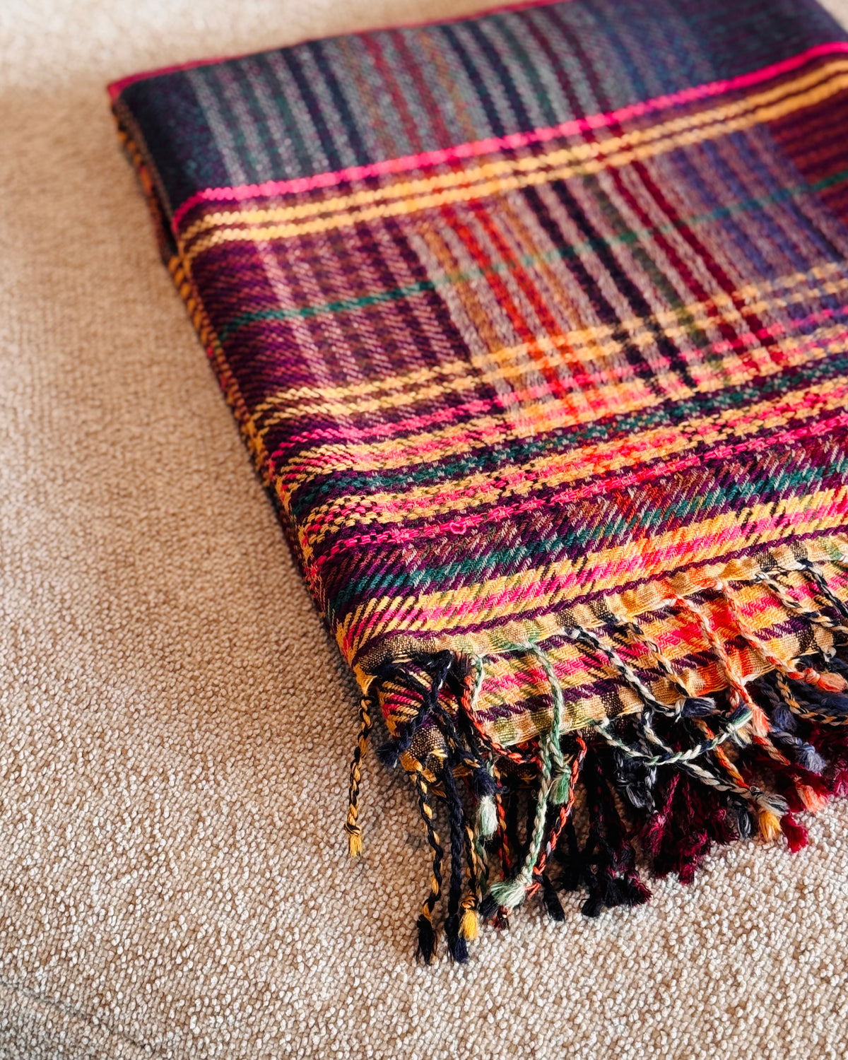 Plaid tartan in lana merino piegato, dettaglio delle frange multicolore