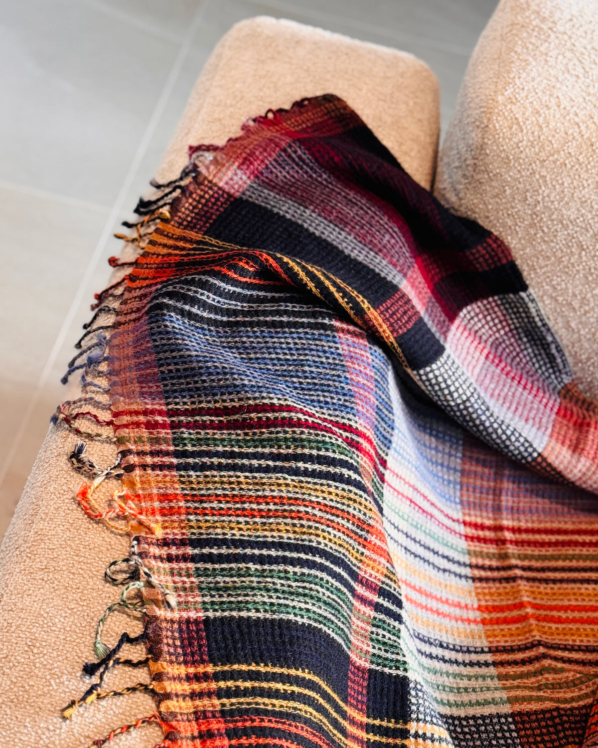 Plaid a quadri drappeggiato sul bracciolo, con frange