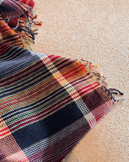 Plaid a quadri blu e arancio che scende dal divano, con frange