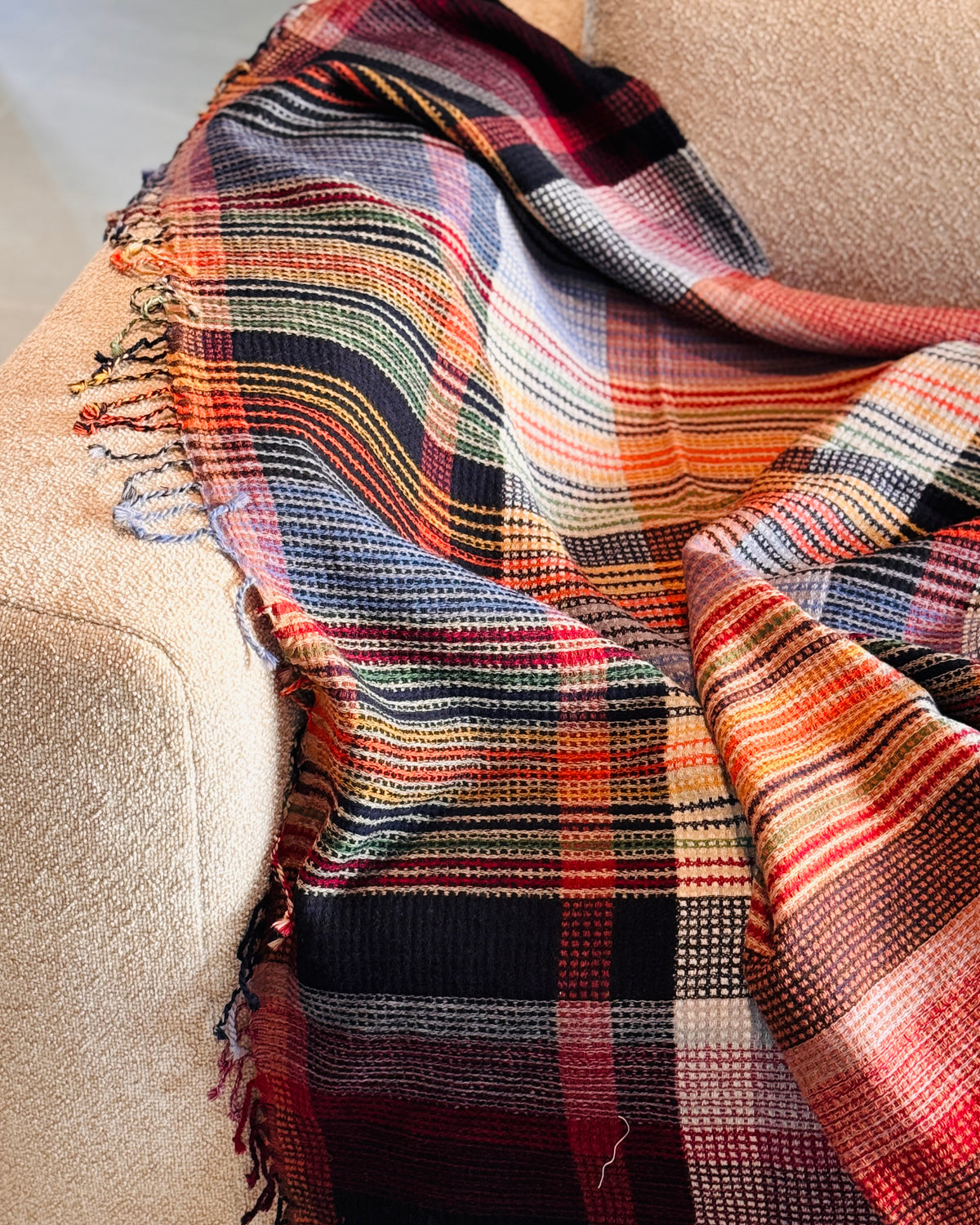 Plaid in lana merino a quadri blu e arancio sul bracciolo del divano