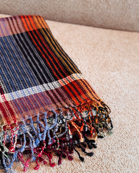 Plaid in lana merino piegato, dettaglio delle frange multicolore