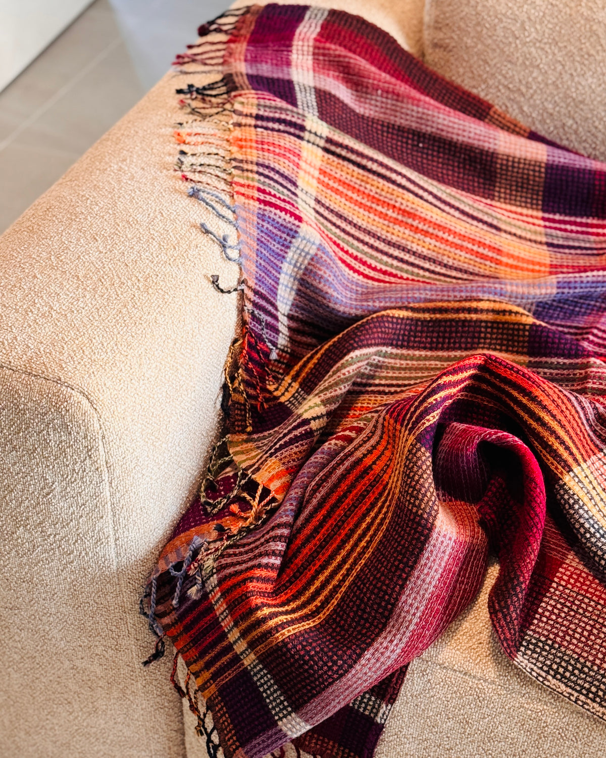 Plaid a quadri viola, rosso e arancio sul bracciolo del divano