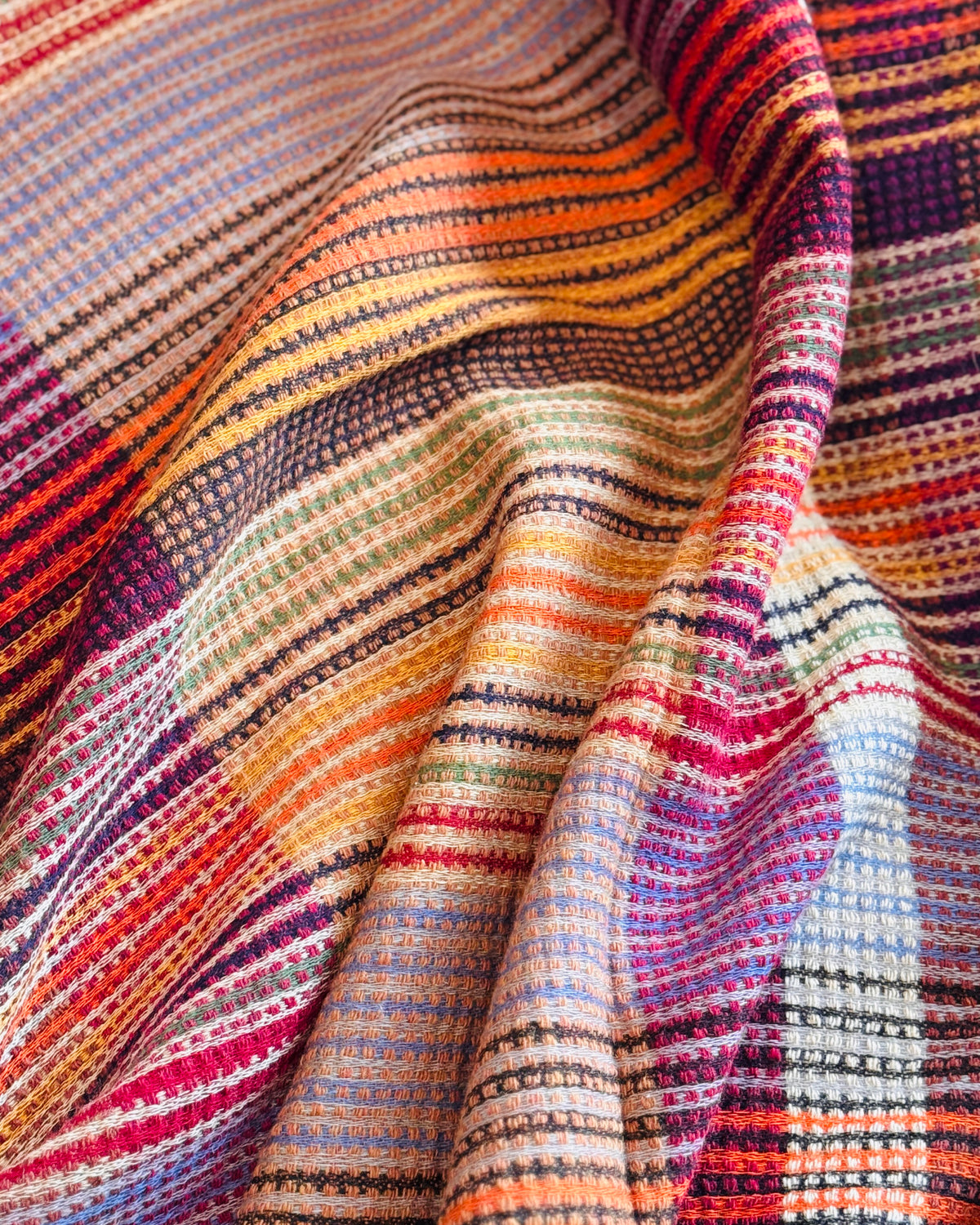 Dettaglio del plaid a quadri: righe arancio, gialle e viola in rilievo