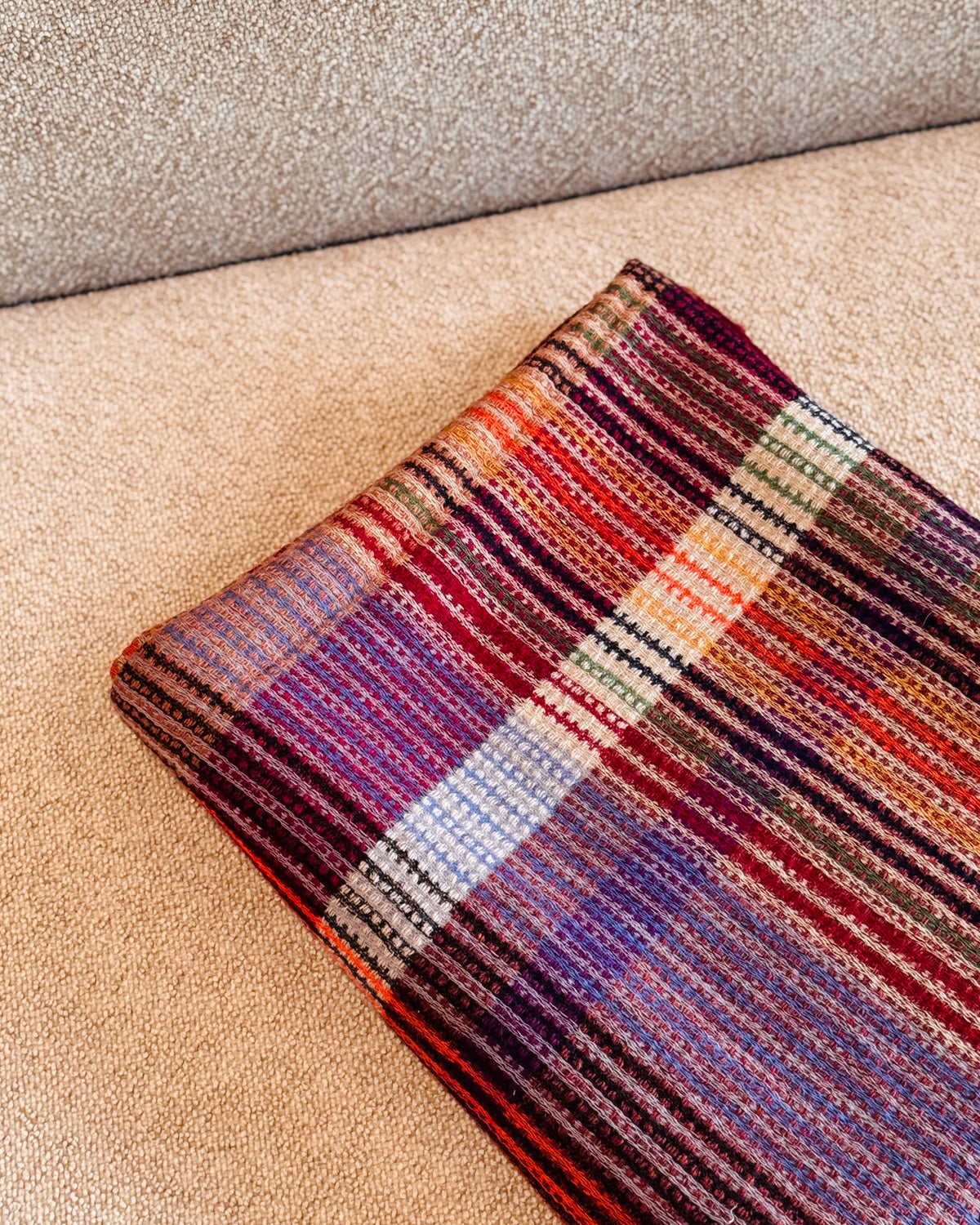 Plaid in lana merino piegato, riquadro viola con righe lilla e crema
