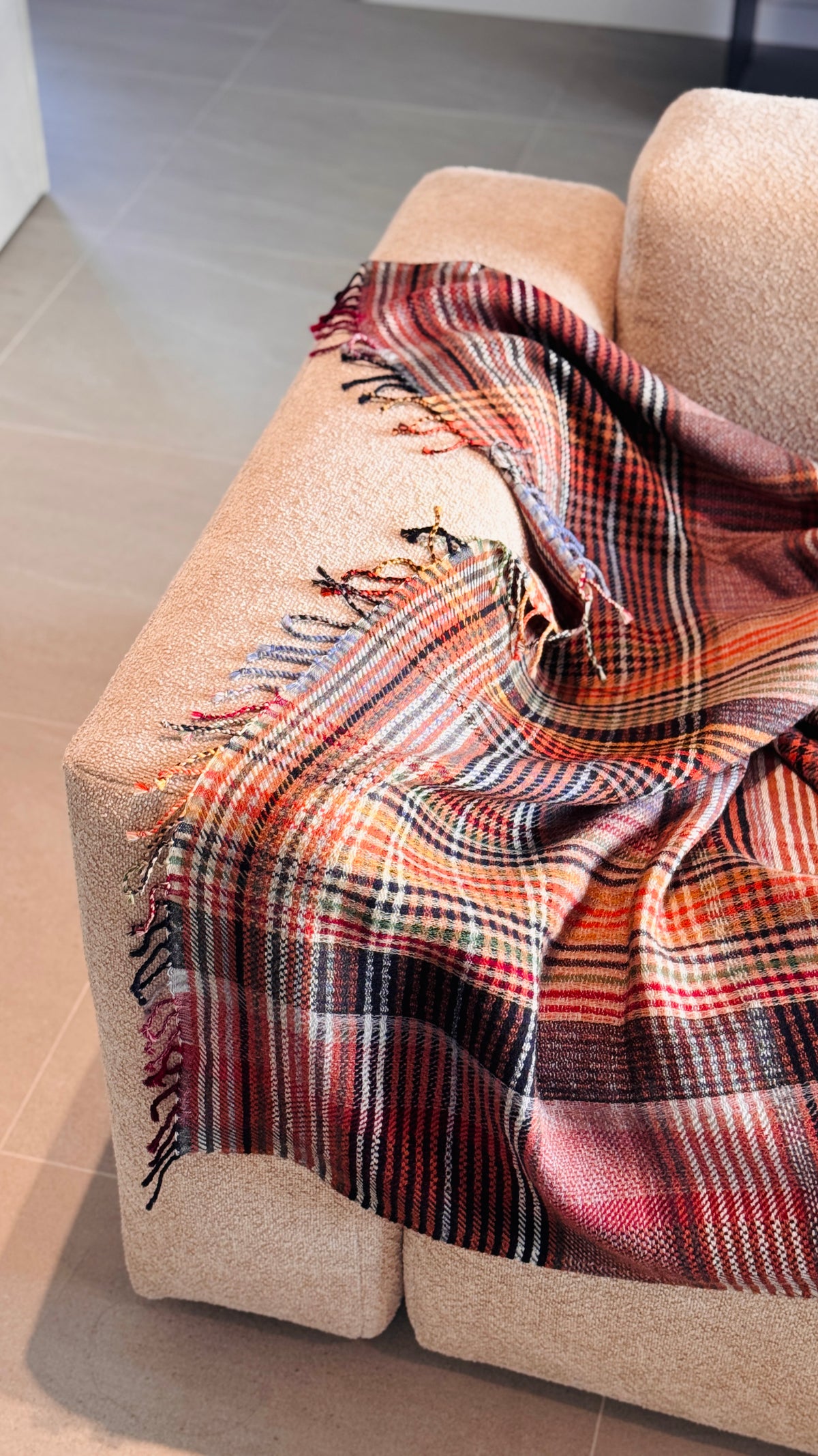 Plaid tartan rosso mattone e arancio sul bracciolo e sulla seduta del divano