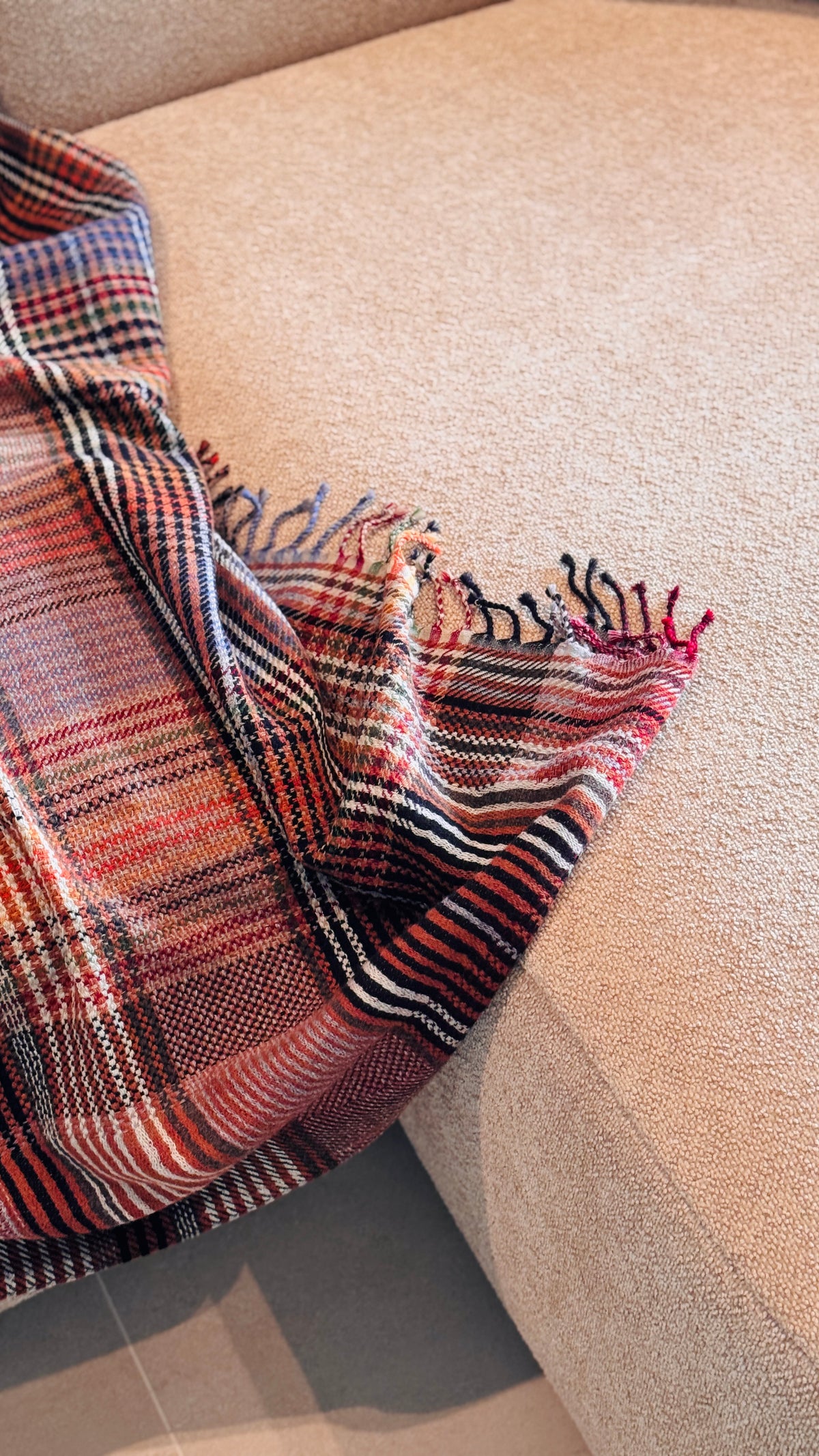 Plaid tartan rosso mattone che scende dalla seduta del divano