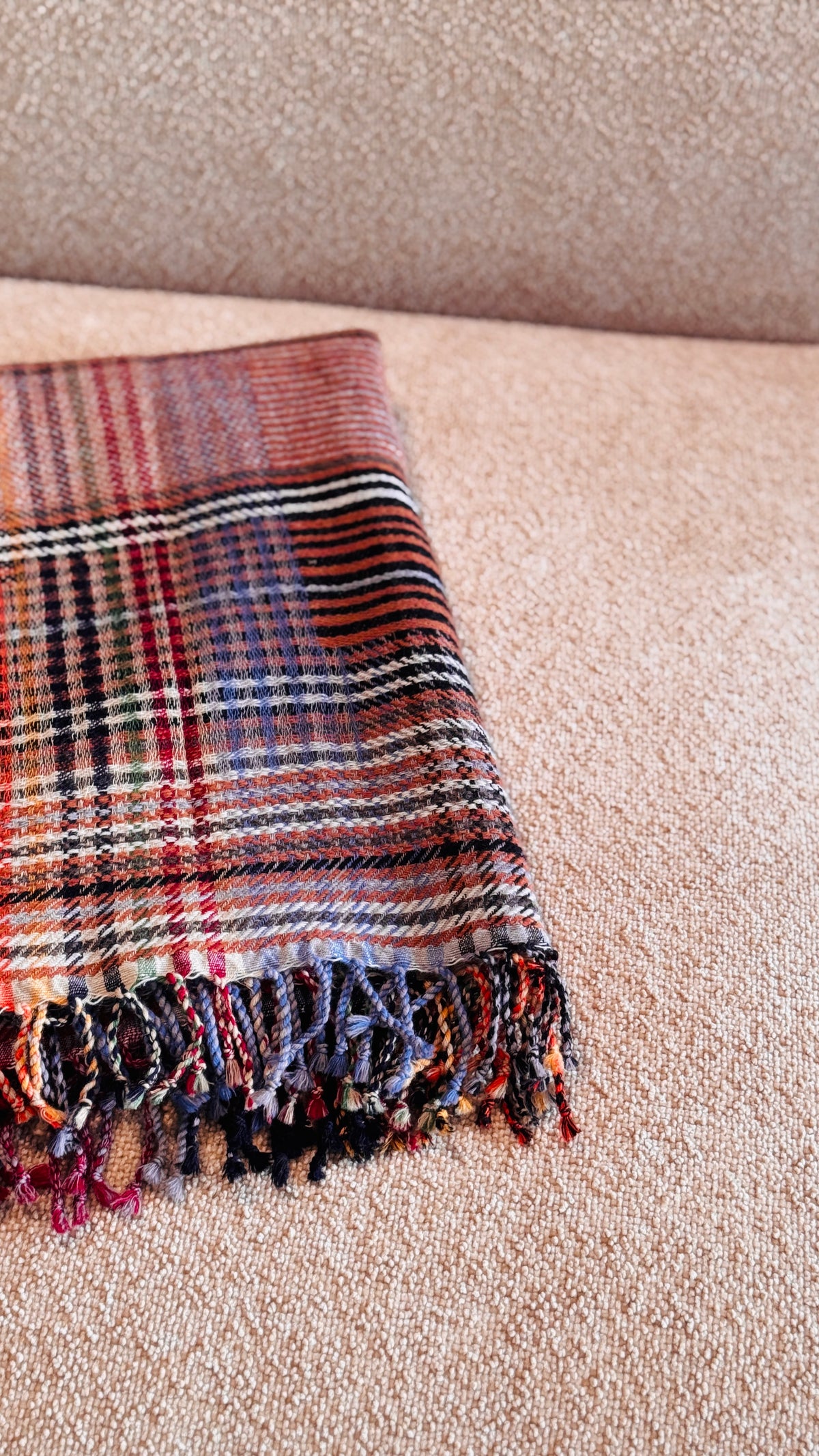 Plaid tartan rosso mattone piegato, dettaglio delle frange multicolore