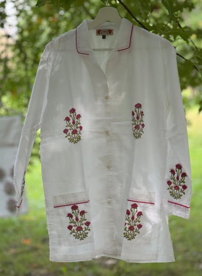 Set pigiama in cotone voile bianco con stampe Buti rosse block print, camicia con piping rosso e pantalone coordinato appesi in giardino.