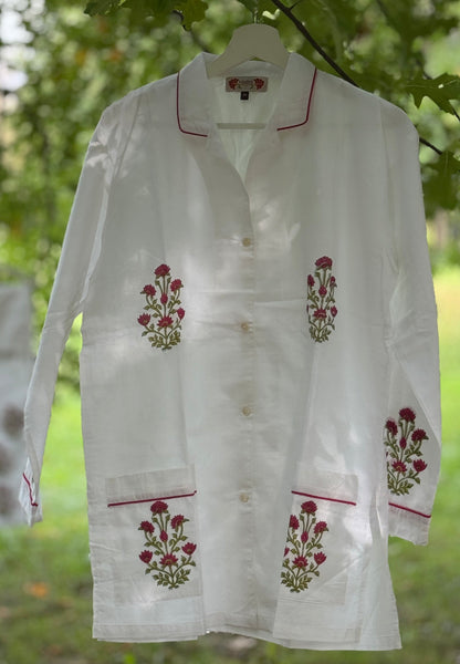 Set pigiama in cotone voile bianco con stampe Buti rosse block print, camicia con piping rosso e pantalone coordinato appesi in giardino.