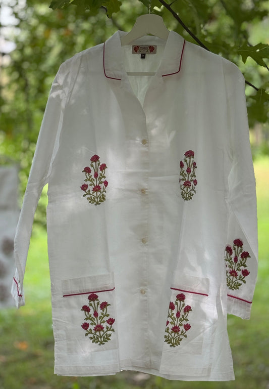 Set pigiama in cotone voile bianco con stampe Buti rosse block print, camicia con piping rosso e pantalone coordinato appesi in giardino.