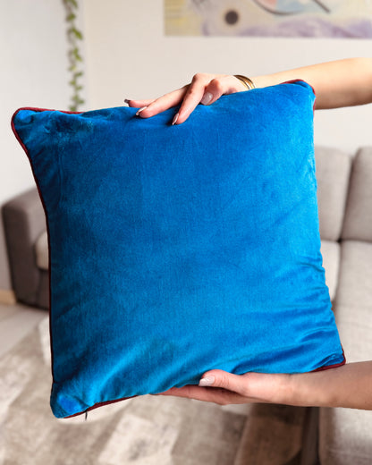Cuscino reversibile 40x40 cm in velluto di cotone: fronte ocra con stampa floreale serigrafica multicolore e retro cyan minimal, con bordo bordeaux.