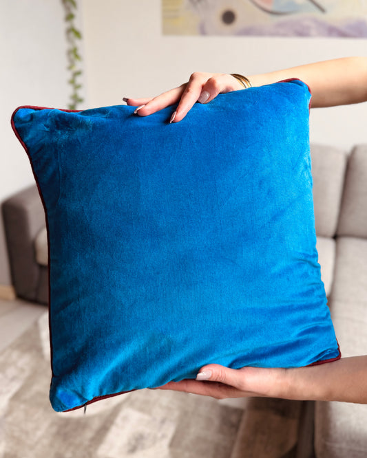 Cuscino reversibile 40x40 cm in velluto di cotone: fronte ocra con stampa floreale serigrafica multicolore e retro cyan minimal, con bordo bordeaux.