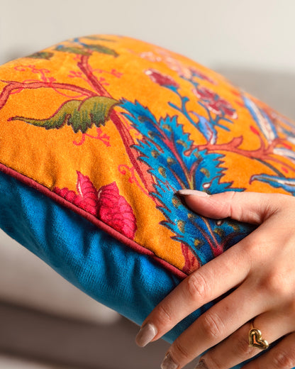Cuscino reversibile 40x40 cm in velluto di cotone: fronte ocra con stampa floreale serigrafica multicolore e retro cyan minimal, con bordo bordeaux.